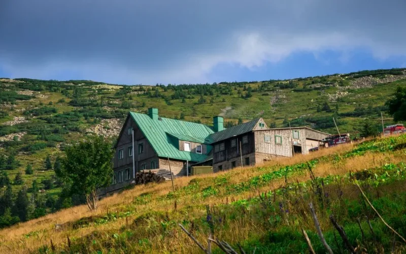 Charming wooden farmhouse nestled in the hills of Karpacz, surrounded by lush greenery and a vibrant landscape.
