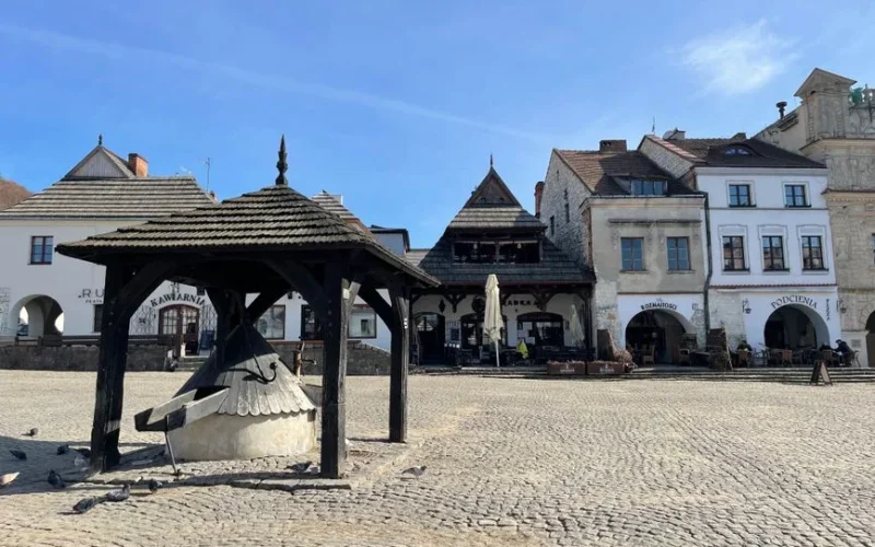 Charming view of the historic town square in Kazimierz Dolny, Poland with traditional architecture under a clear blue sky.