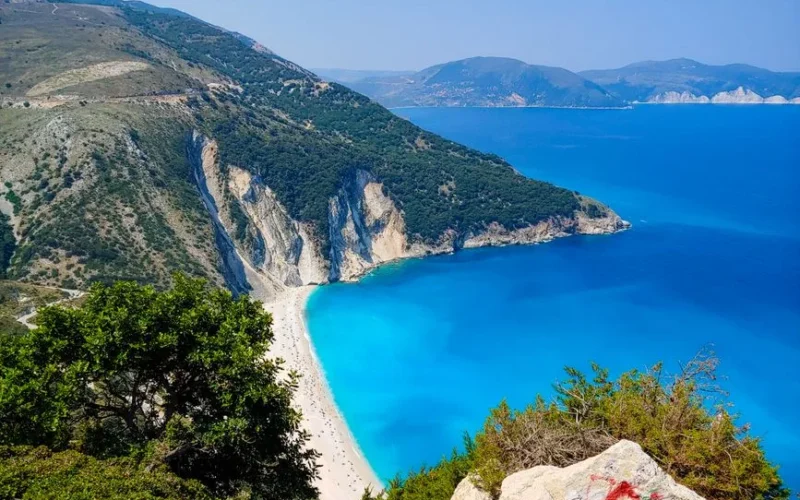 Stunning aerial view of Myrtos Beach with turquoise waters and rugged cliffs on Kefalonia Island, Greece.