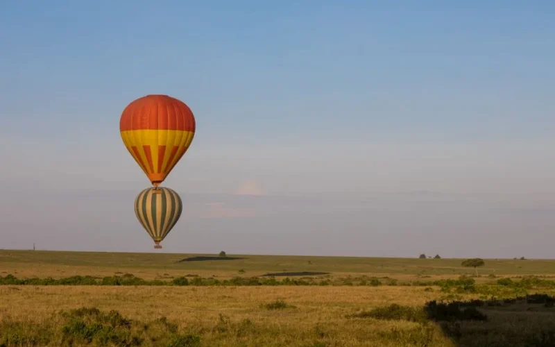 Hot air balloons floating over the Maasai Mara savannah during sunrise in Kenya.