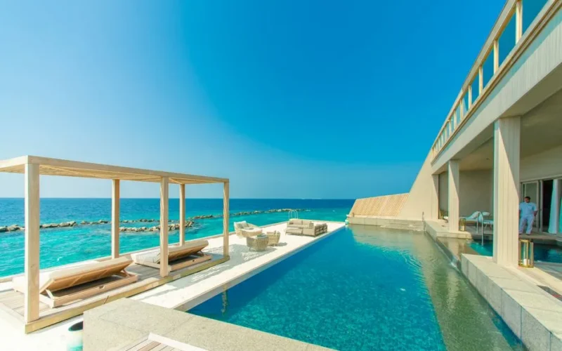 Stunning view of a luxury resort in Maldives with an infinity pool overlooking the ocean.