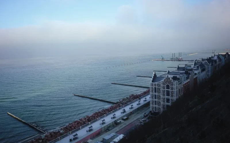 Scenic coastal view featuring a city promenade and waterfront buildings in daylight.