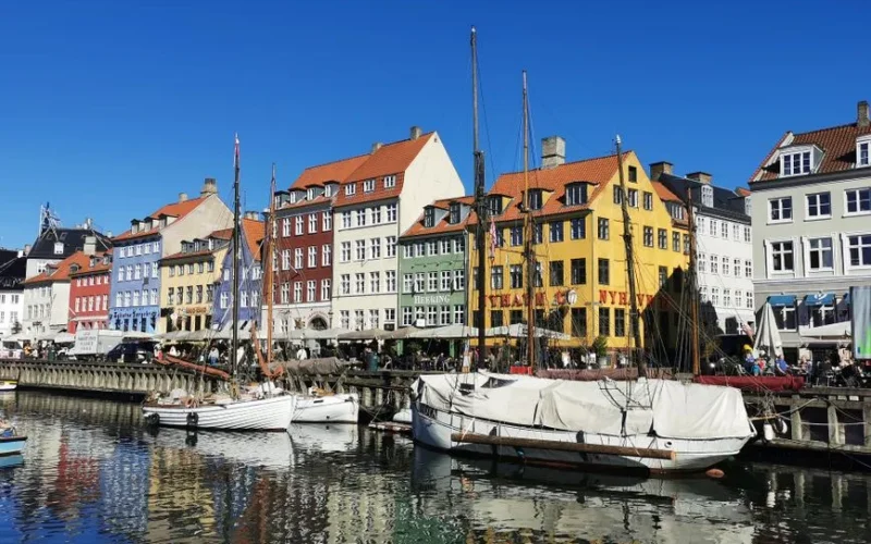 Vibrant view of colorful buildings and boats at Nyhavn harbor, a famous spot in Copenhagen, Denmark.