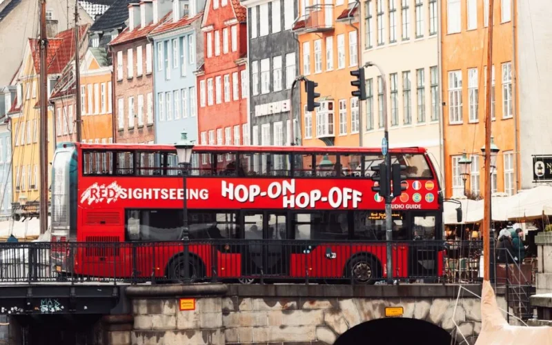 Colorful Nyhavn canal and red sightseeing bus in Copenhagen, Denmark.