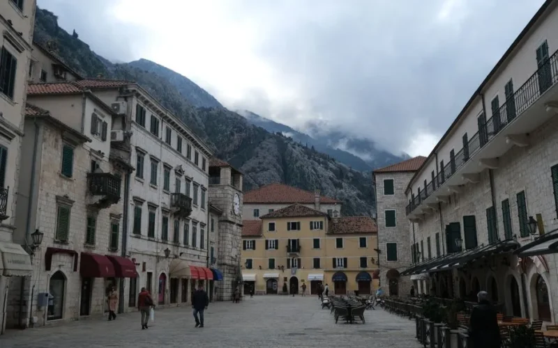 Charming medieval square in Kotor with mountainous backdrop and classic architecture.