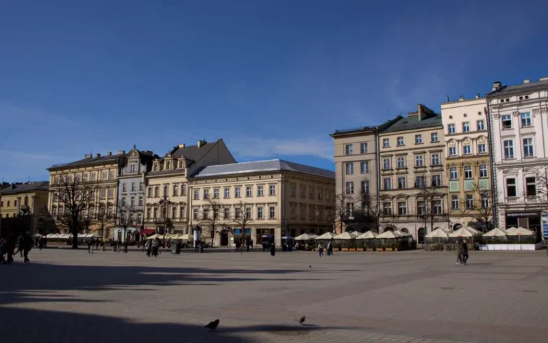 Explore the historic buildings in Kraków's vibrant Main Square on a sunny day.