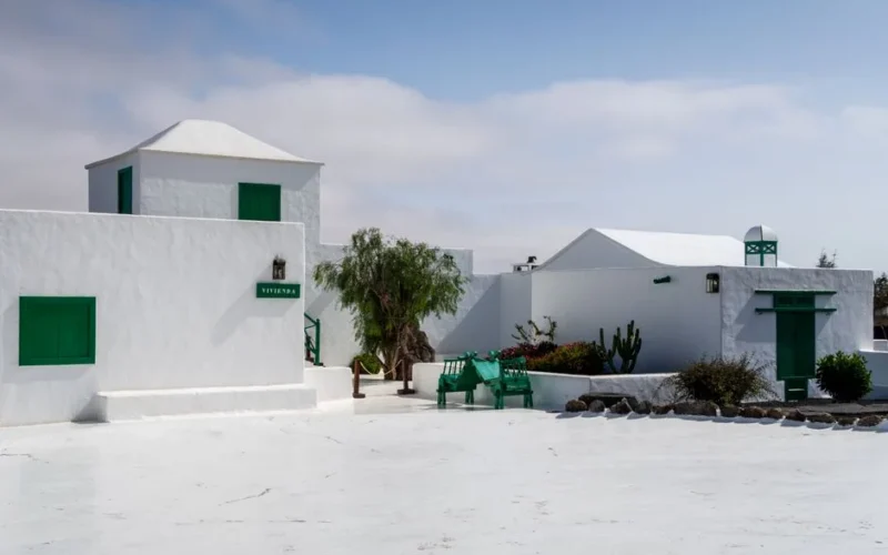 Charming white buildings with green accents under a blue sky in Lanzarote, Spain.