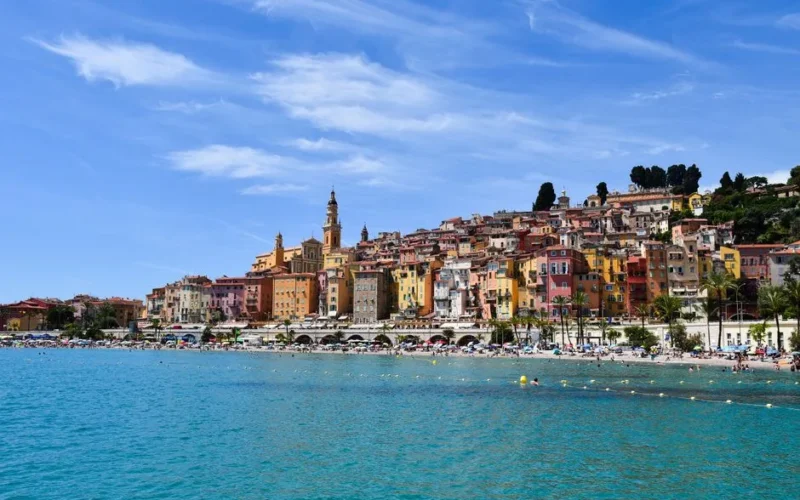 A vibrant view of Menton's coastline, showcasing colorful buildings and azure waters on a sunny day.
