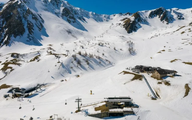 An aerial shot of a scenic ski resort nestled in snow-covered alpine mountains during winter.