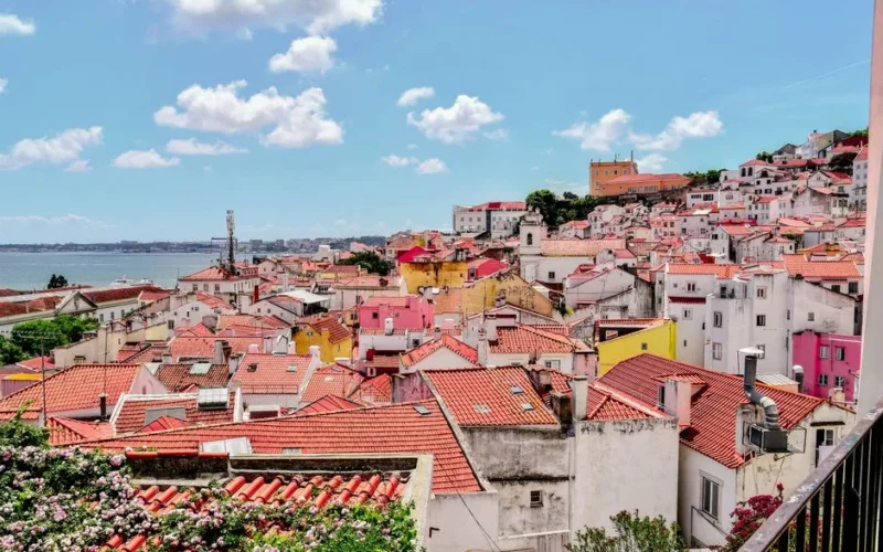 Vibrant Lisbon rooftops with stunning river view under a bright blue sky.