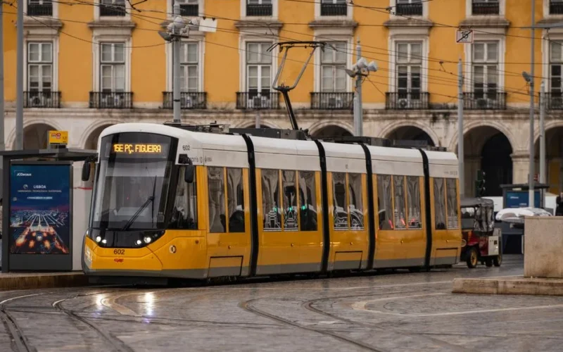 A classic yellow tram passing through Lisbon, Portugal's historic streets, showcasing Portuguese architecture.