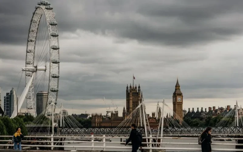 Iconic view of the London Eye and Big Ben on a cloudy day along the Thames.