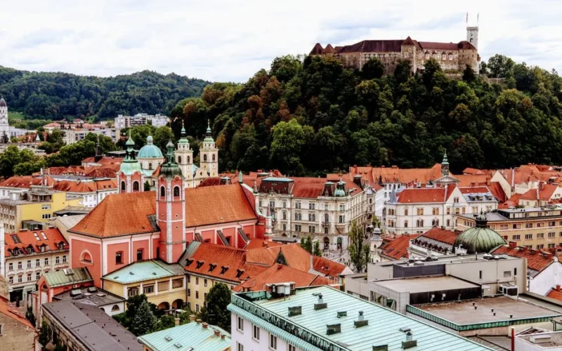 A scenic view of Ljubljana's vibrant old town with the famous castle atop a green hill.