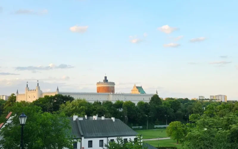 Skyline view of Lublin Castle, Poland, with lush greenery and blue sky.