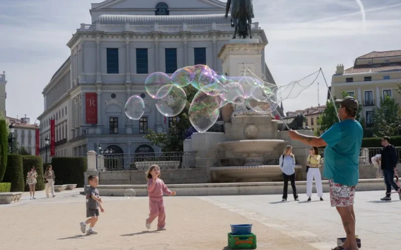 Joyful children playing with bubbles in front of Teatro Real, Madrid.