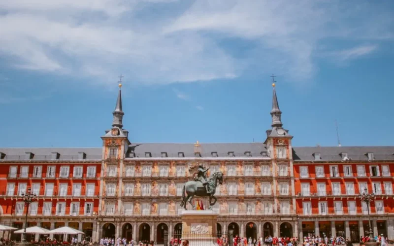 A view of the Plaza Mayor in Madrid, showcasing its historical architecture under a clear blue sky.