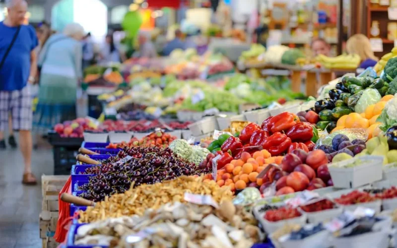 Colorful assortment of fresh fruits and vegetables in a bustling outdoor market scene.