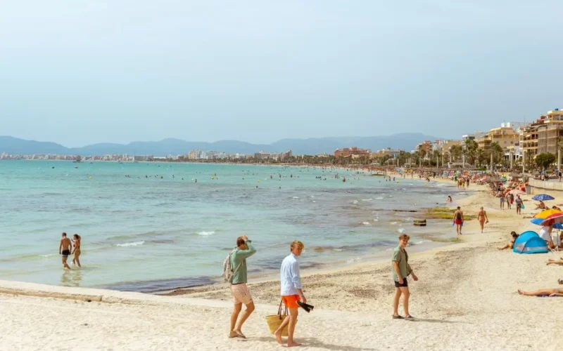 Idyllic summer day at a lively beach in Mallorca with people enjoying the sun and sea.