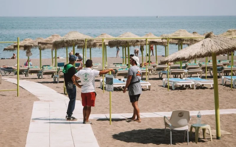 Visitors on sand with umbrellas and sun loungers on a sunny Málaga beach.