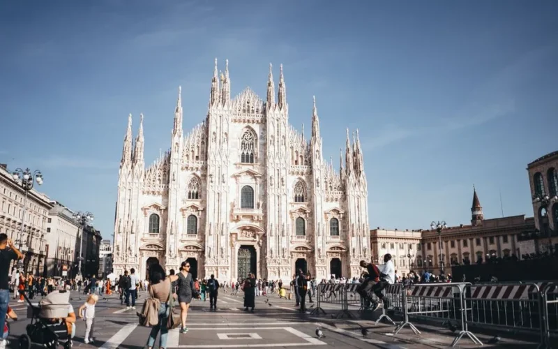 Capture of the majestic Milan Cathedral, showcasing its stunning Gothic architecture in a lively city square.