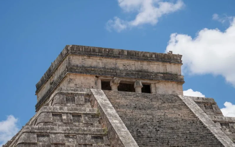 Close-up view of El Castillo pyramid in Chichén Itzá, showcasing ancient Mayan architecture under a vibrant blue sky.