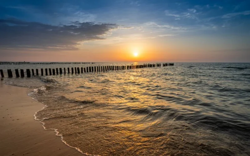 Captivating sunset over the Baltic Sea with golden reflections on the beach at Mielno, Poland.