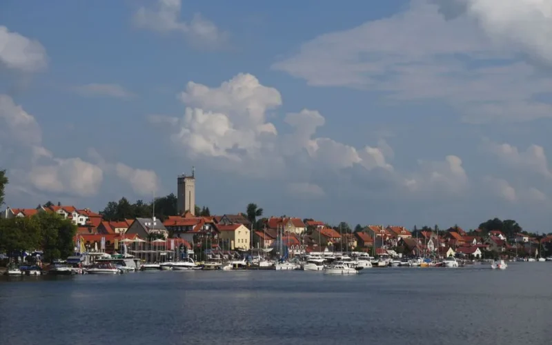 Picturesque view of Augustów with boats docked by the waterfront under a blue sky.