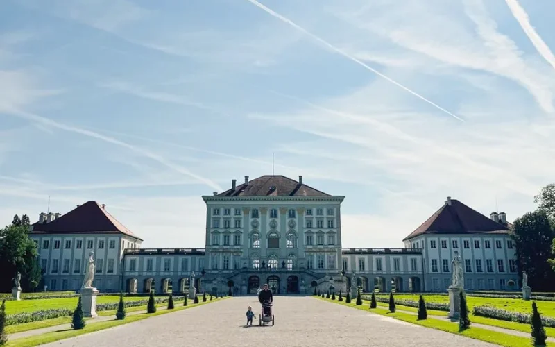 A scenic view of Nymphenburg Palace with visitors on a sunny day in Munich, Germany.