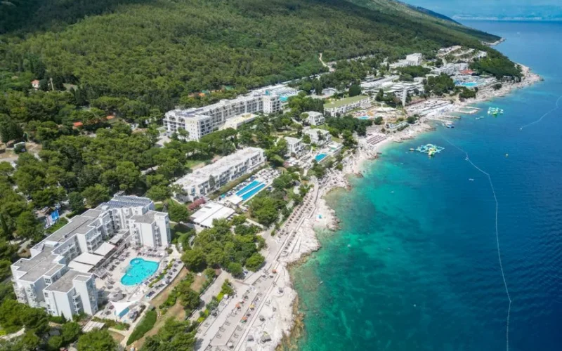 Discover Rabac's coastline with turquoise waters and resort-lined shores from an aerial perspective.