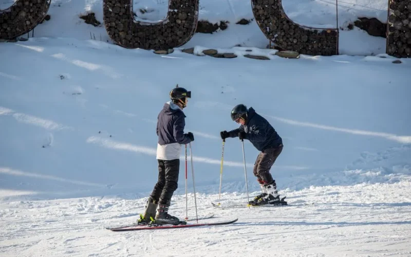 Two adult skiers in full gear enjoying a winter day on the slopes, capturing the essence of winter sports fun.