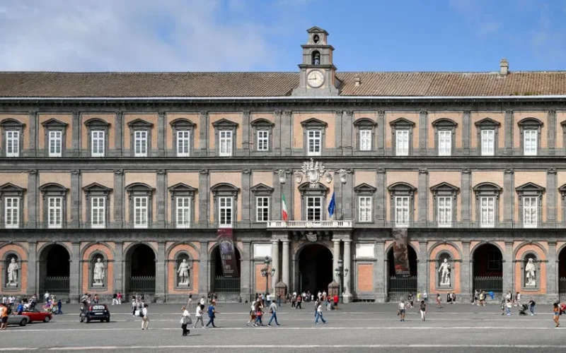 People strolling in Piazza del Plebiscito with the Royal Palace facade in Naples, Italy.