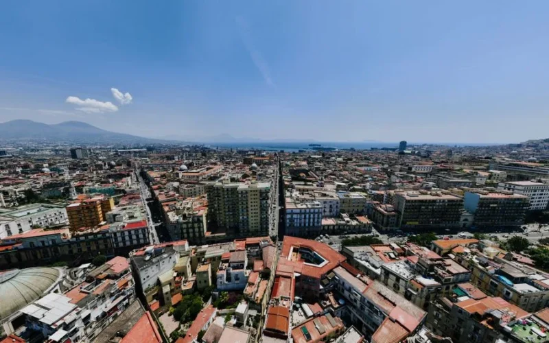 Panoramic aerial shot of Naples, Italy, showcasing cityscape and Mount Vesuvius.