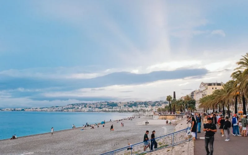 Bustling beachfront in Nice with scenic ocean views and palm-lined promenade.