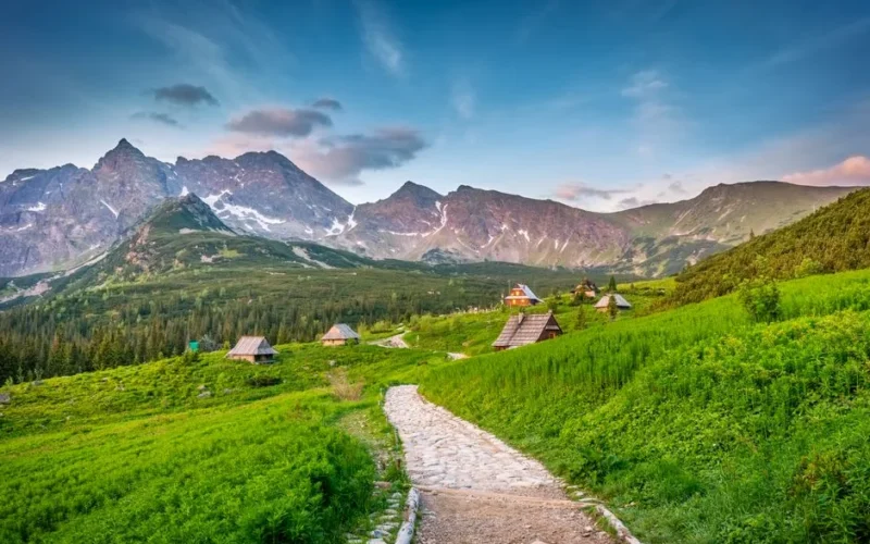 Beautiful summer landscape of Hala Gąsienicowa in Tatra Mountains with green meadows and rustic cabins.