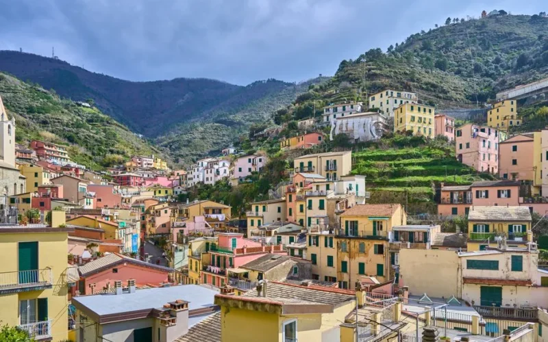 Vibrant hillside village in Cinque Terre, Italy with colorful buildings and scenic mountain backdrop.