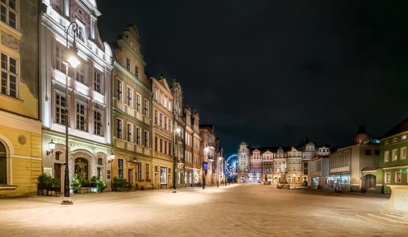 Charming nighttime view of illuminated old town square buildings in Poznań, Poland.