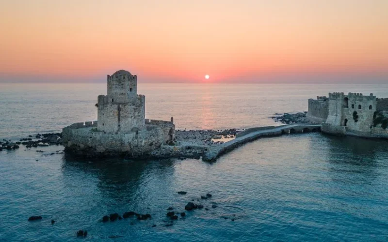 A stunning aerial view of Methoni Castle at sunset over the serene sea in Greece.