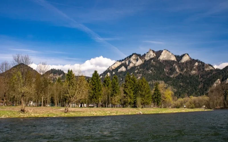 Majestic landscape of Three Crowns Mountain with trees and a river in springtime.
