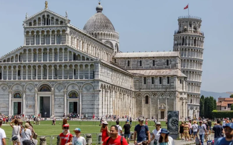 Crowds explore the Pisa Cathedral and iconic Leaning Tower on a sunny day in Pisa, Italy.