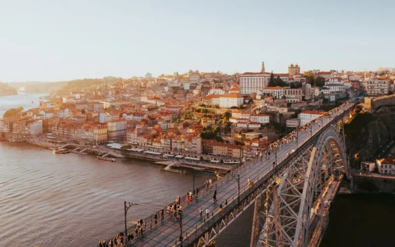 A stunning aerial view of Porto's historic cityscape and Dom Luís I Bridge over the Douro River at sunset.