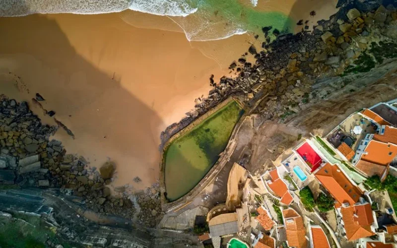 Stunning aerial shot of Cascais beach and coastal village with vibrant rooftops and rocky shoreline.
