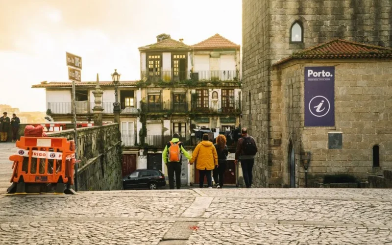 Group of people walking down cobblestone streets in Porto, Portugal, showcasing historic architecture.
