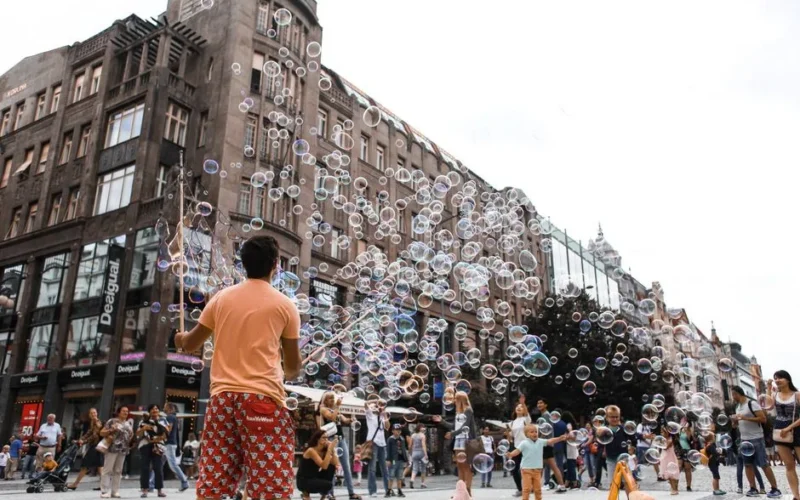 A street performer entertaining a crowd with soap bubbles in a bustling urban square, showcasing lively city life.