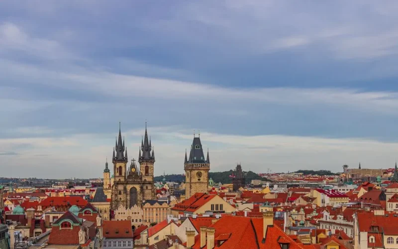 A scenic aerial view of Prague's Old Town Square featuring iconic historic towers under a vibrant sky.