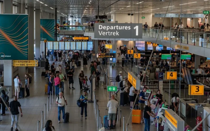 Crowds in the departure area of Amsterdam's Schiphol Airport, showcasing bustling travel activity.