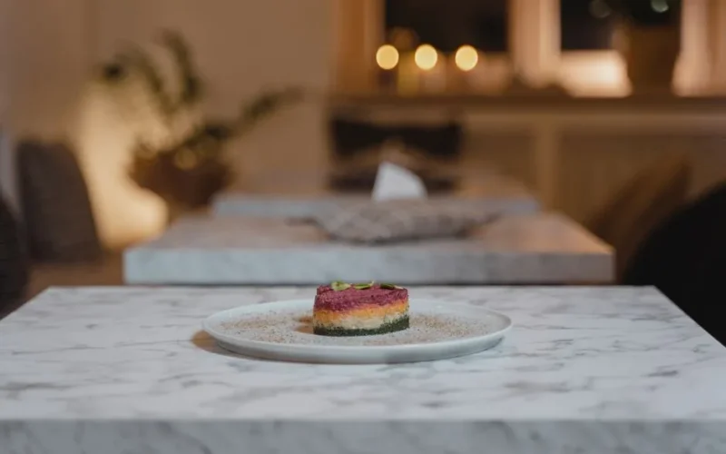 A beautifully presented gourmet dish on a marble table in a cozy restaurant setting with warm lighting.