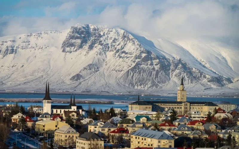 Beautiful view of Reykjavik with snowy mountains in the backdrop under a clear blue sky.