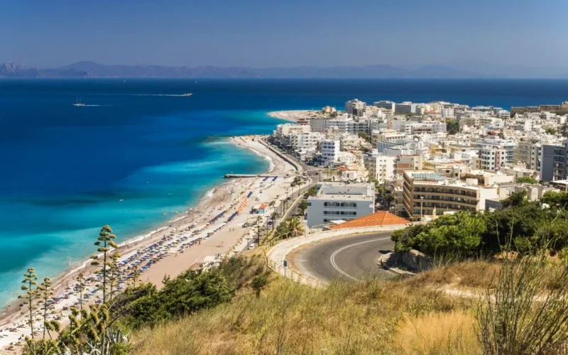 Stunning aerial view of Rhodes, Greece with its beautiful beach and vibrant cityscape under a clear blue sky.