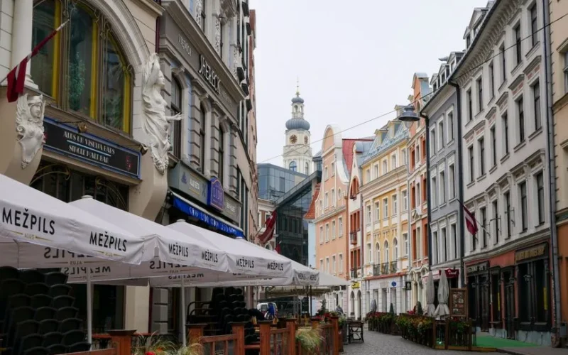 Scenic view of a vibrant street in Old Riga, showcasing traditional architecture and outdoor cafes.