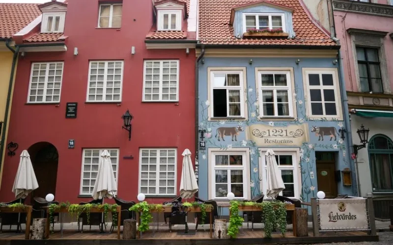 Colorful historic buildings in Riga's Old Town with outdoor cafe seating under umbrellas.